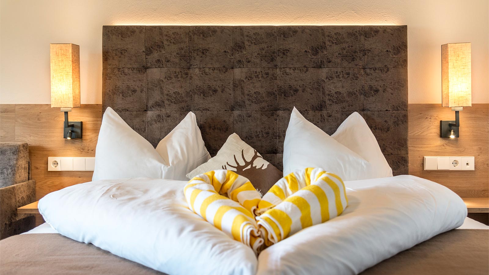 ein schön dekoriertes Bett im Hotel Alpenfrieden, die Bettwäsche ist in Herzform gefaltet