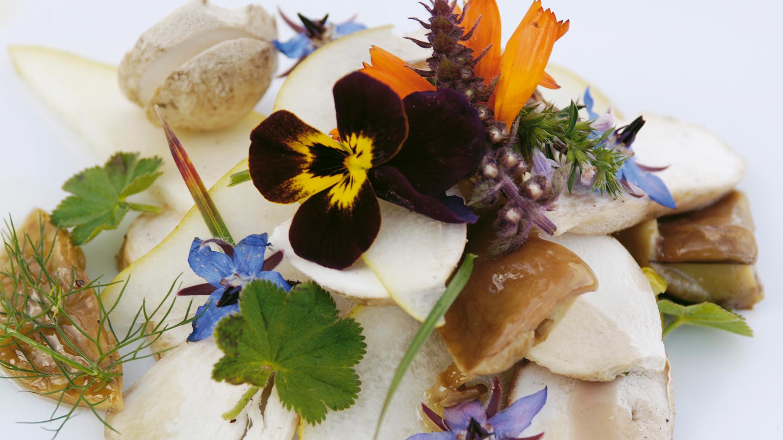 ein ausgefallenes Gericht mit Steinpilzen und Blumen im Hotel Alpenfrieden bei Meransen