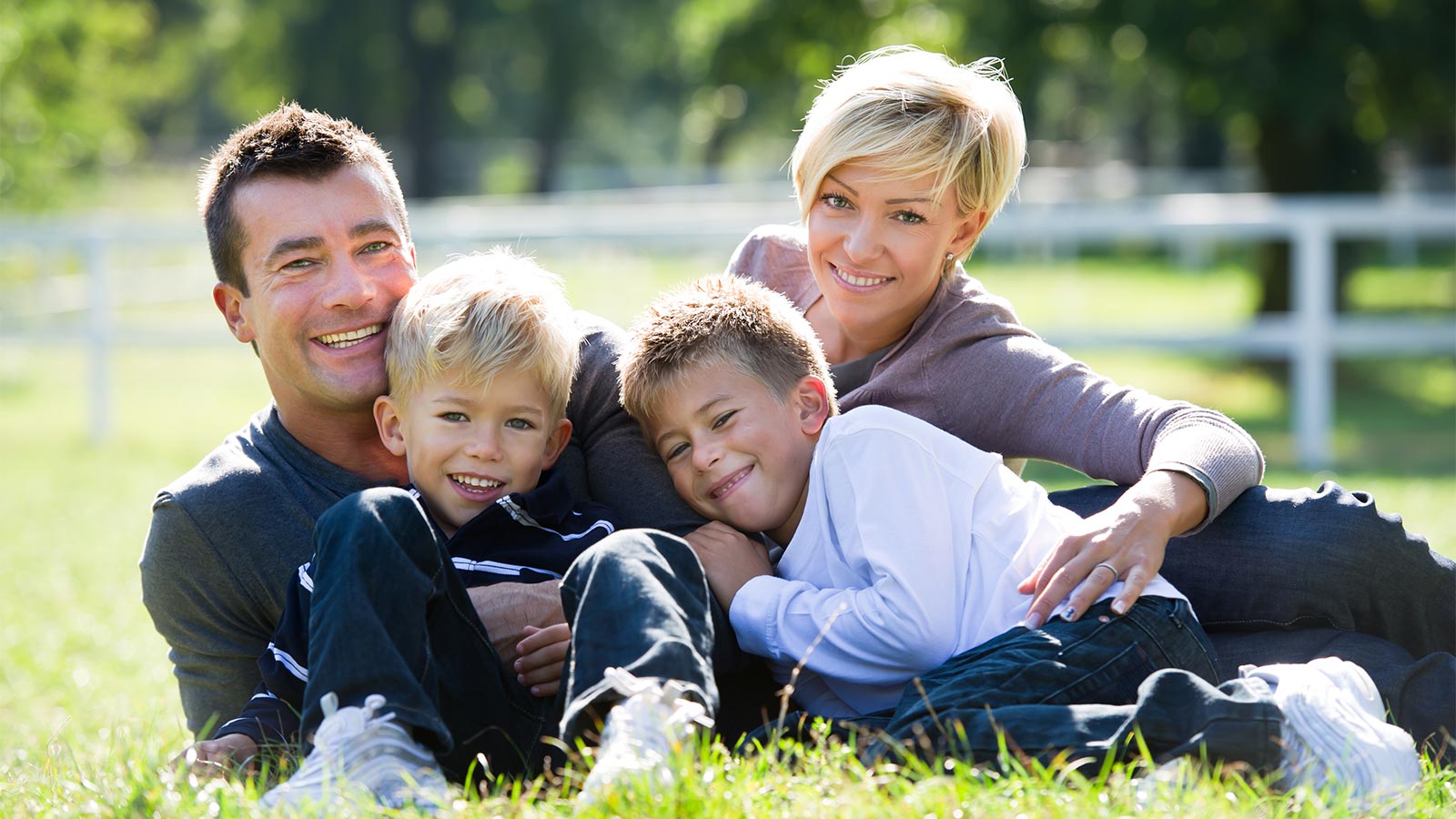 una famiglia - i genitori e due bambini - felici su un prato d'estate vicino a Maranza