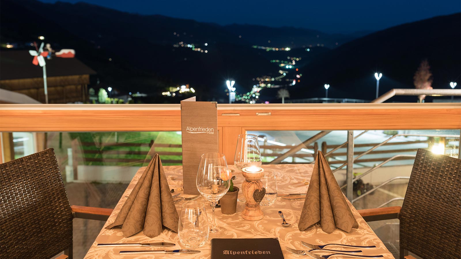 a prepared dining table on the terrace at Hotel Alpenfrieden on a warm summer night