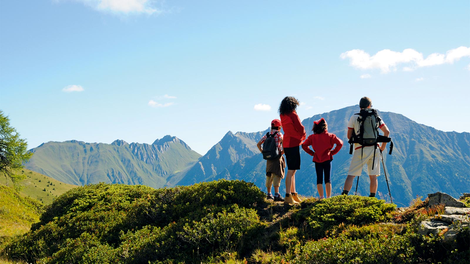 eine Familie steht am Felsrand und blickt in die Ferne während einer Wanderung