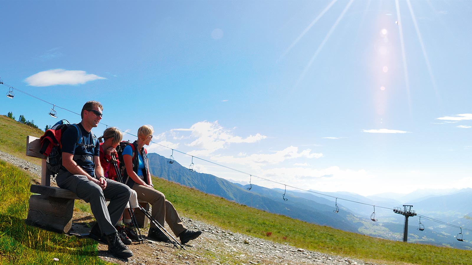 una famiglia riposa su una panca durante un'escursione in montagna d'estate