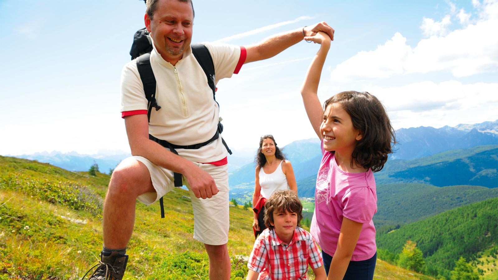 ein Vater mit seinen drei Kindern auf der Alm im Sommer