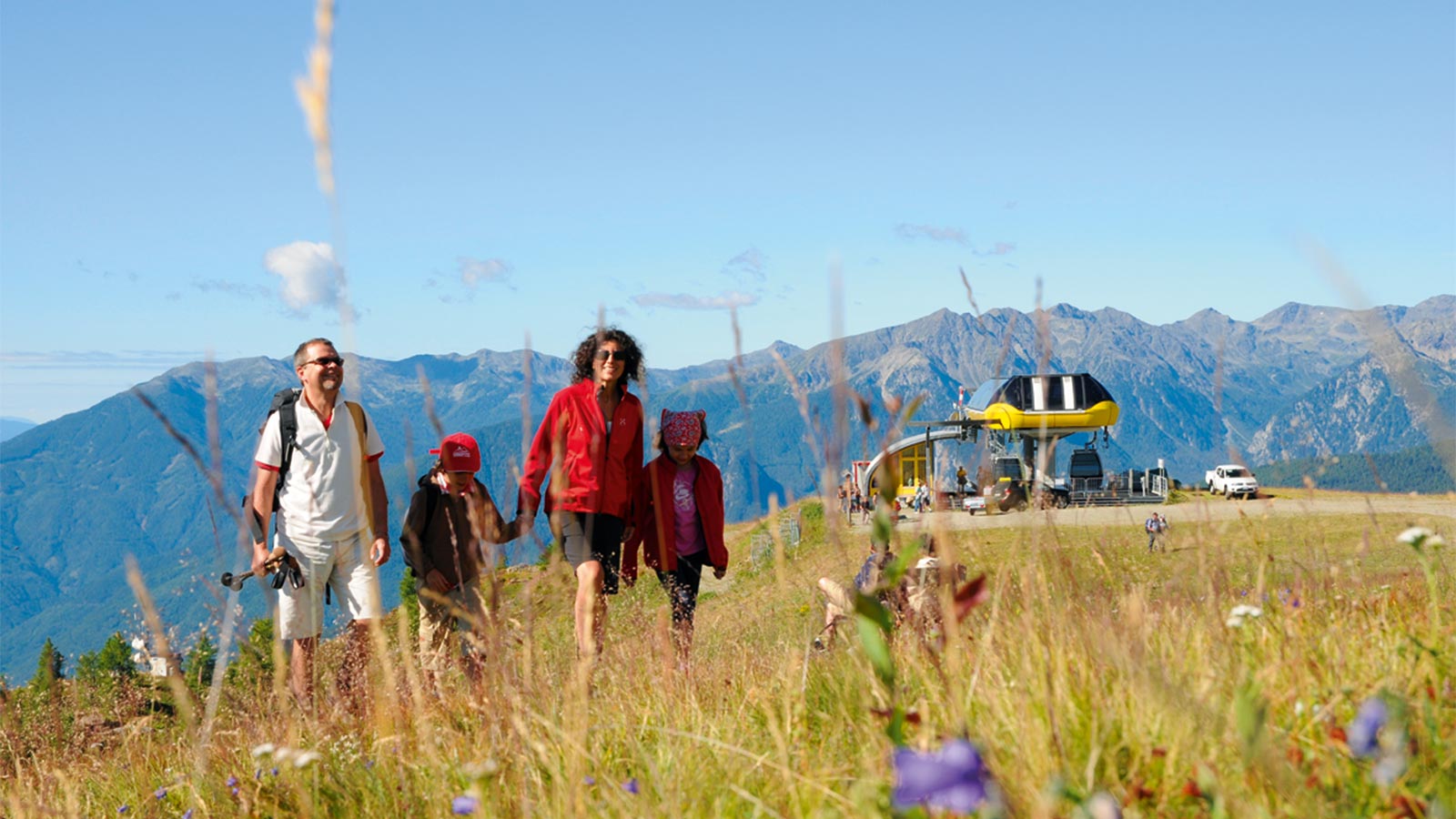 una famiglia passeggia su un prato fiorito durante l'estate nell'area sci e malghe Rio Pusteria